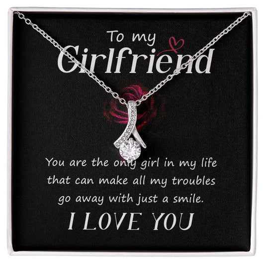 Alluring Beauty Necklace with ribbon pendant in white and yellow gold finishes displayed in soft touch packaging