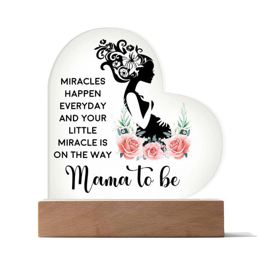 Heart-shaped acrylic plaque reading "Mama to Be - Miracles Happen Everyday" on wooden base
